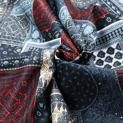 A patchwork-style fabric print featuring a repetitive arrangement of square and rectangular blocks. Each block is filled with intricate navy blue, red, and cream-coloured bandana and paisley motifs, creating a dense, geometric, and traditional textile pattern.