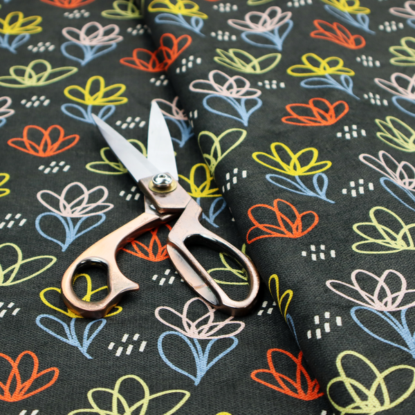 A black fabric print featuring a modern, repeating pattern of colourful doodle-style floral outlines. The flowers are drawn in vibrant yellow, orange, pink, and light blue, accented by small white dash marks, creating a playful and artistic aesthetic.