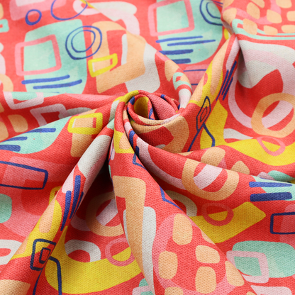 A vibrant fabric print featuring an abstract, mid-century modern design. The pattern consists of overlapping geometric shapes—circles, rectangles, and arches—in a lively palette of coral, bright yellow, teal, and soft peach on a coral-red background, creating a playful and retro aesthetic.