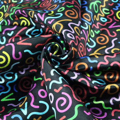 A black fabric print featuring a retro, 90s-inspired pattern of colourful, hand-drawn-style doodles. The design includes vibrant neon swirls, squiggles, and V-shapes in shades of pink, yellow, blue, orange, and green, creating a nostalgic, high-energy, and playful aesthetic.