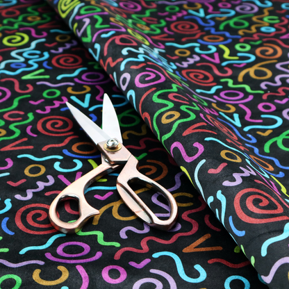 A black fabric print featuring a retro, 90s-inspired pattern of colourful, hand-drawn-style doodles. The design includes vibrant neon swirls, squiggles, and V-shapes in shades of pink, yellow, blue, orange, and green, creating a nostalgic, high-energy, and playful aesthetic.