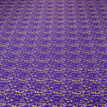 A vibrant fabric print featuring a dense, abstract pattern of bright yellow, sharp-edged shapes scattered across a deep, solid purple background. The design creates a textured, dynamic, and modern look.