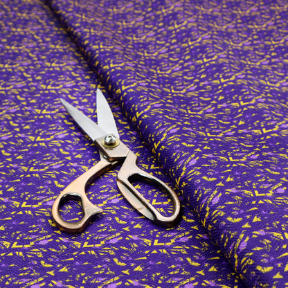 A vibrant fabric print featuring a dense, abstract pattern of bright yellow, sharp-edged shapes scattered across a deep, solid purple background. The design creates a textured, dynamic, and modern look.