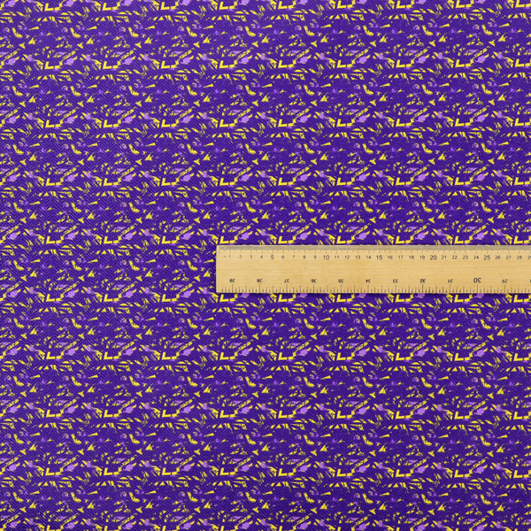A vibrant fabric print featuring a dense, abstract pattern of bright yellow, sharp-edged shapes scattered across a deep, solid purple background. The design creates a textured, dynamic, and modern look.