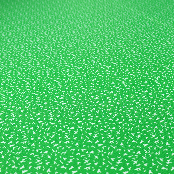 A bright, vibrant green fabric print featuring a repetitive, minimalist pattern of small, white, irregular flecks or specks. The design creates a textured, clean, and modern look.