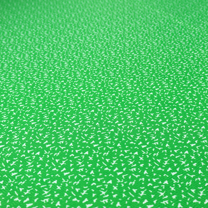 A bright, vibrant green fabric print featuring a repetitive, minimalist pattern of small, white, irregular flecks or specks. The design creates a textured, clean, and modern look.