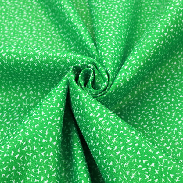 A bright, vibrant green fabric print featuring a repetitive, minimalist pattern of small, white, irregular flecks or specks. The design creates a textured, clean, and modern look.