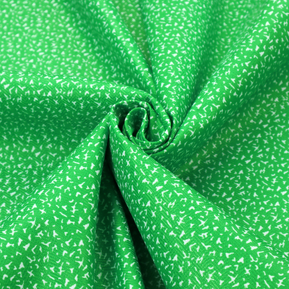A bright, vibrant green fabric print featuring a repetitive, minimalist pattern of small, white, irregular flecks or specks. The design creates a textured, clean, and modern look.