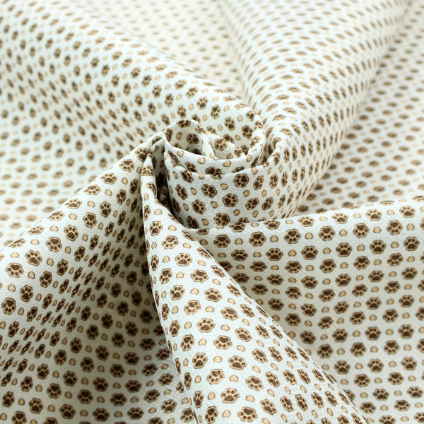 Micro-scale ditsy fabric pattern featuring rows of tiny brown paw prints and beige hearts arranged in a dense polka dot grid on a pale blue background.