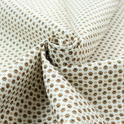 Micro-scale ditsy fabric pattern featuring rows of tiny brown paw prints and beige hearts arranged in a dense polka dot grid on a pale blue background.