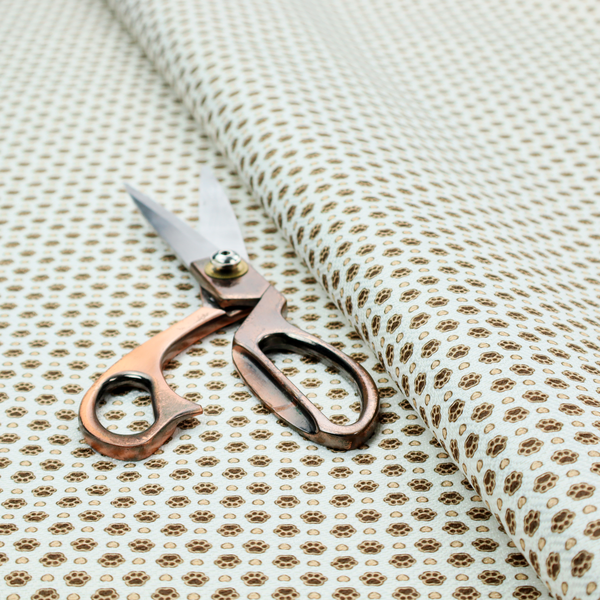 Micro-scale ditsy fabric pattern featuring rows of tiny brown paw prints and beige hearts arranged in a dense polka dot grid on a pale blue background.