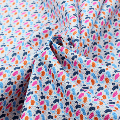 This fabric features a playful, confetti-inspired terrazzo pattern set against a light grey, speckled background.