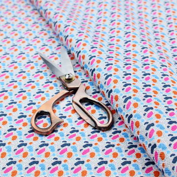 This fabric features a playful, confetti-inspired terrazzo pattern set against a light grey, speckled background.