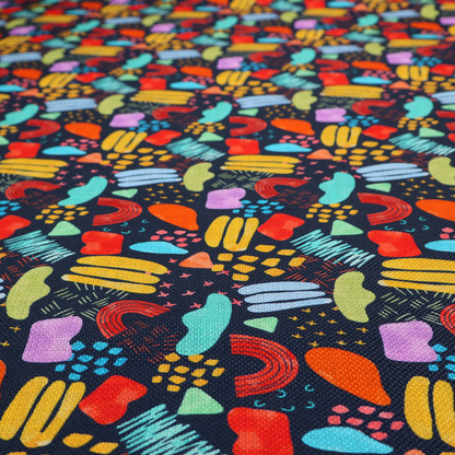 This fabric features a lively, abstract pattern set against a deep navy background. The design is filled with a dense, colourful array of hand-drawn shapes, including squiggles, small arches, and organic blobs in a vibrant palette of yellow, red, orange, teal, light blue, and purple.
