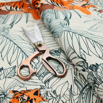 This fabric features a repeating botanical and wildlife pattern set against a light cream and grey background. The design showcases tigers in two poses—some walking and some resting—interspersed with detailed line drawings of large tropical leaves and hibiscus flowers.
