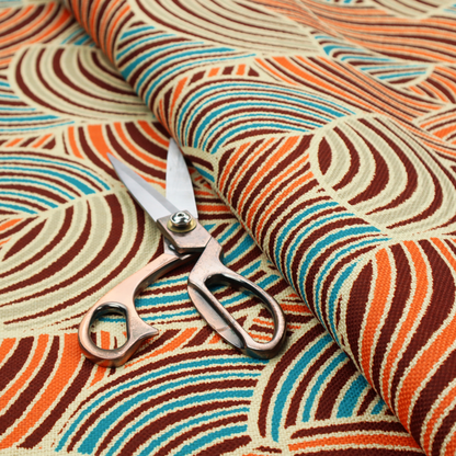 This fabric features a geometric, fan-like pattern composed of overlapping semi-circular arcs. The design creates a dynamic sense of movement through a vibrant colour palette of burnt orange, deep brown, bright turquoise, and cream.