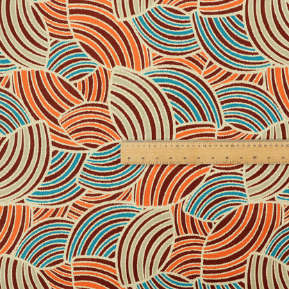 This fabric features a geometric, fan-like pattern composed of overlapping semi-circular arcs. The design creates a dynamic sense of movement through a vibrant colour palette of burnt orange, deep brown, bright turquoise, and cream.