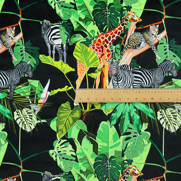 This fabric features a lush, vibrant jungle scene set against a deep black background. The pattern is filled with a dense variety of tropical foliage, including large monstera and palm leaves in multiple shades of green.