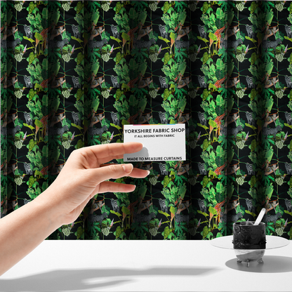 The fabric used to create these made-to-measure curtains is a fabric features a lush, vibrant jungle scene set against a deep black background. The pattern is filled with a dense variety of tropical foliage, including large monstera and palm leaves in multiple shades of green.