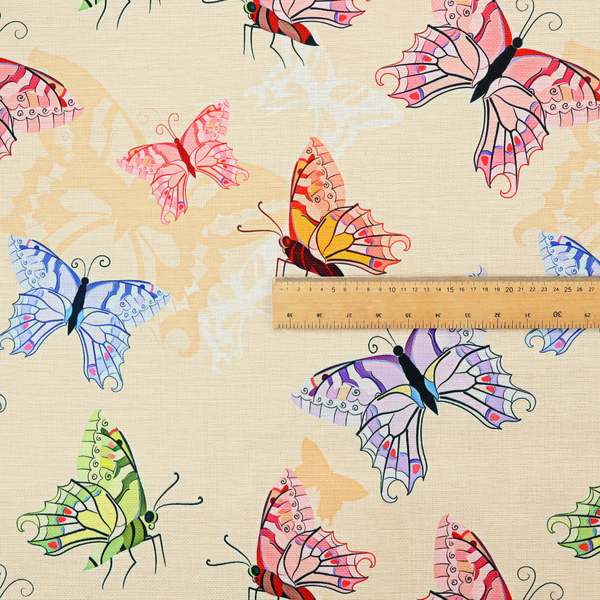 This fabric features a whimsical, repeating pattern of colourful butterflies scattered across a light beige, textured background. The butterflies are rendered in various sizes and a vibrant colour palette, including shades of pink, purple, lime green, and soft blue, with delicate black wing detailing.