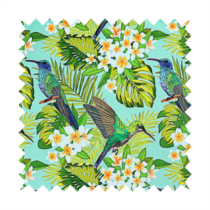 This fabric features a vibrant, tropical pattern set against a bright turquoise background. The design showcases hummingbirds in various poses—some perched and others in flight—surrounded by clusters of white plumeria flowers and lush, layered palm and monstera leaves in shades of green and yellow.
