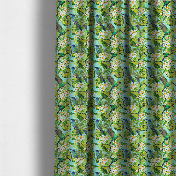 The fabric used to create these made-to-measure curtains is a fabric features a vibrant, tropical pattern set against a bright turquoise background. The design showcases hummingbirds in various poses—some perched and others in flight—surrounded by clusters of white plumeria flowers and lush, layered palm and monstera leaves in shades of green and yellow.