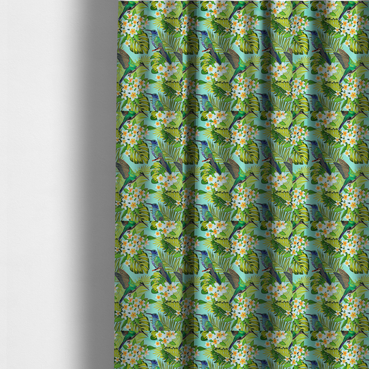 The fabric used to create these made-to-measure curtains is a fabric features a vibrant, tropical pattern set against a bright turquoise background. The design showcases hummingbirds in various poses—some perched and others in flight—surrounded by clusters of white plumeria flowers and lush, layered palm and monstera leaves in shades of green and yellow.