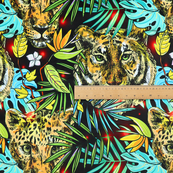 This fabric features a bold, artistic jungle-themed pattern set against a dark black background. The design is a dense, repeating collage of wildlife portraits, featuring alternating heads of leopards and tigers with intense, detailed expressions.