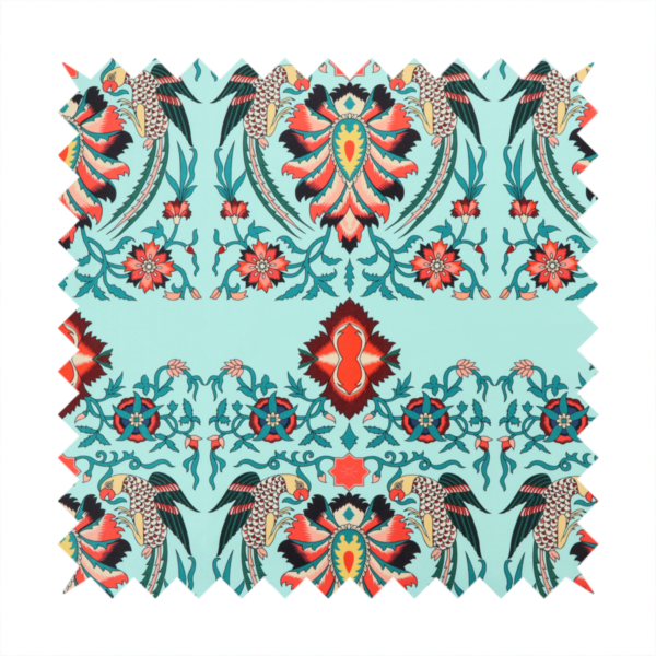 This fabric features an intricate, symmetrical folk-art inspired pattern set against a soft, light turquoise background. The design showcases stylized birds facing toward central, ornate floral bursts, rendered in a bold colour palette of vibrant red, deep orange, teal, and charcoal.
