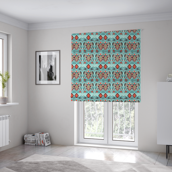 The fabric used to create these Roman blinds is a fabric features an intricate, symmetrical folk-art inspired pattern set against a soft, light turquoise background. The design showcases stylized birds facing toward central, ornate floral bursts, rendered in a bold colour palette of vibrant red, deep orange, teal, and charcoal.