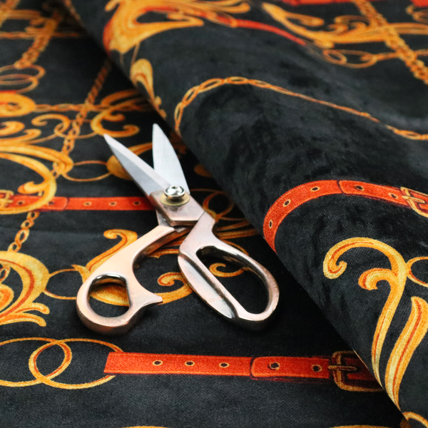 Luxury fashion fabric pattern featuring gold baroque acanthus scrolls layered over a grid of interlocking gold chains and red-orange leather straps on a black background.