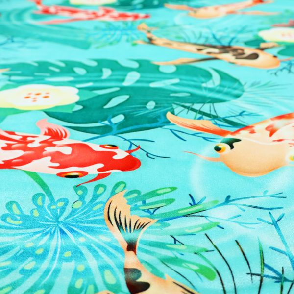 Patterned fabric featuring vibrant orange, white, and dark blue koi fish swimming among lush tropical monstera leaves, water ripples, and white flowers on a light teal background.