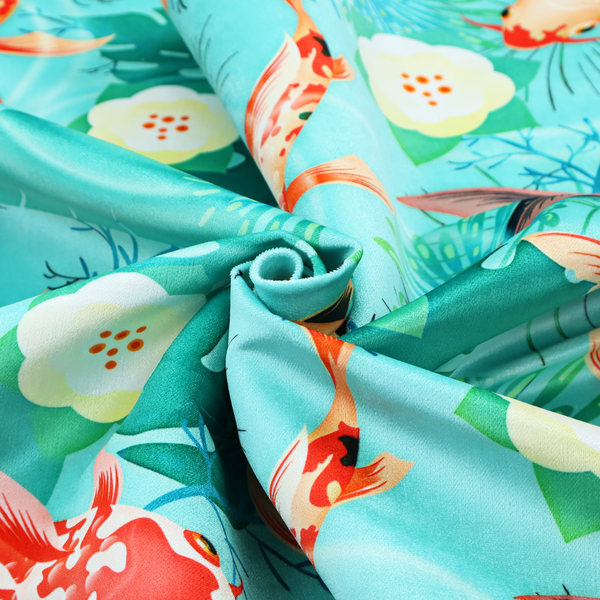 Patterned fabric featuring vibrant orange, white, and dark blue koi fish swimming among lush tropical monstera leaves, water ripples, and white flowers on a light teal background.