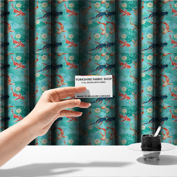 The fabric used to create these made-to-measure curtains is a patterned fabric featuring vibrant orange, white, and dark blue koi fish swimming among lush tropical monstera leaves, water ripples, and white flowers on a light teal background.