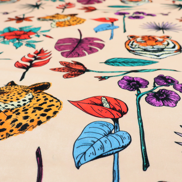 Patterned fabric featuring a repeating design of tiger and leopard heads interspersed with vibrant tropical flowers, orchids, and palm leaves on a cream background.