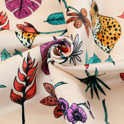 Patterned fabric featuring a repeating design of tiger and leopard heads interspersed with vibrant tropical flowers, orchids, and palm leaves on a cream background.