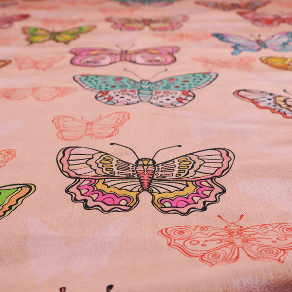Patterned fabric featuring a whimsical, repeating design of colourful butterflies in various patterns and shades—including orange, teal, pink, and yellow—scattered among faint, outline-style butterfly silhouettes on a soft, dusty pink background.