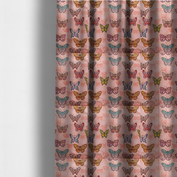 The fabric used to create these made-to-measure curtains is a patterned fabric featuring a whimsical, repeating design of colourful butterflies in various patterns and shades—including orange, teal, pink, and yellow—scattered among faint, outline-style butterfly silhouettes on a soft, dusty pink background.