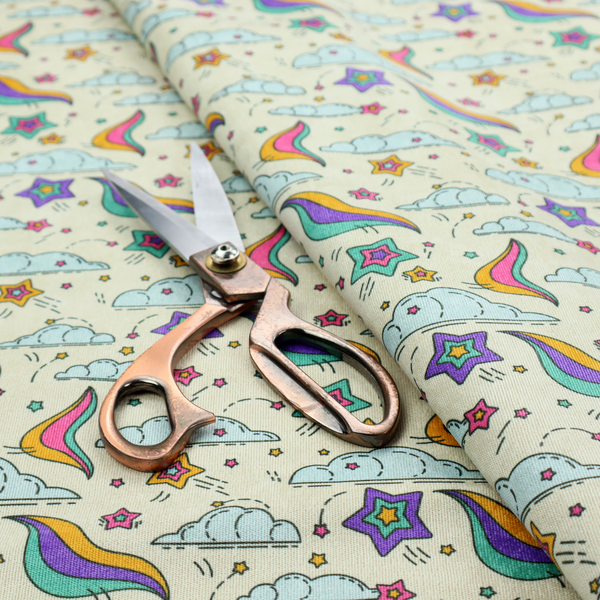 A whimsical, repeating fabric pattern featuring illustrated clouds, colourful shooting stars, and twinkling stars on a light cream background.