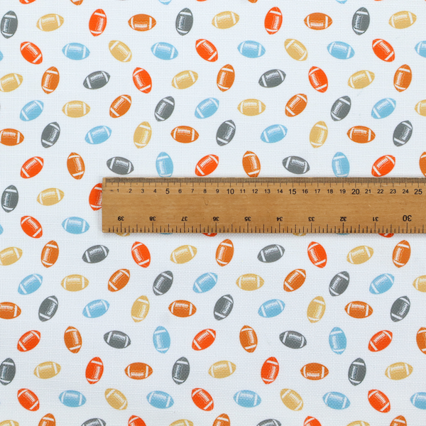 A white fabric featuring a playful, repeating pattern of small American footballs.