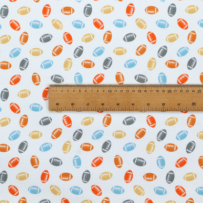 A white fabric featuring a playful, repeating pattern of small American footballs.