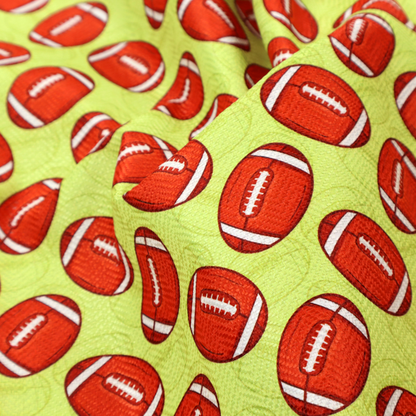 A vibrant lime green fabric featuring an orderly, repeating pattern of American footballs.