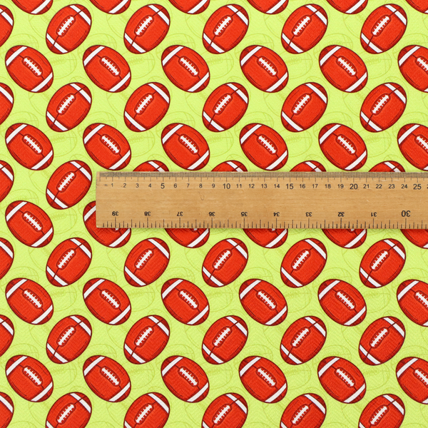 A vibrant lime green fabric featuring an orderly, repeating pattern of American footballs.