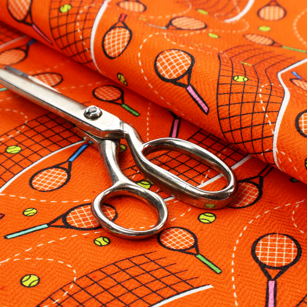 a vibrant burnt orange fabric featuring a dynamic, repeating tennis-themed pattern.
