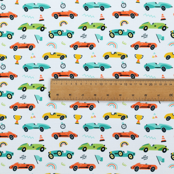 A fabric featuring a whimsical, repeating pattern of vintage-style racing cars and track accessories.