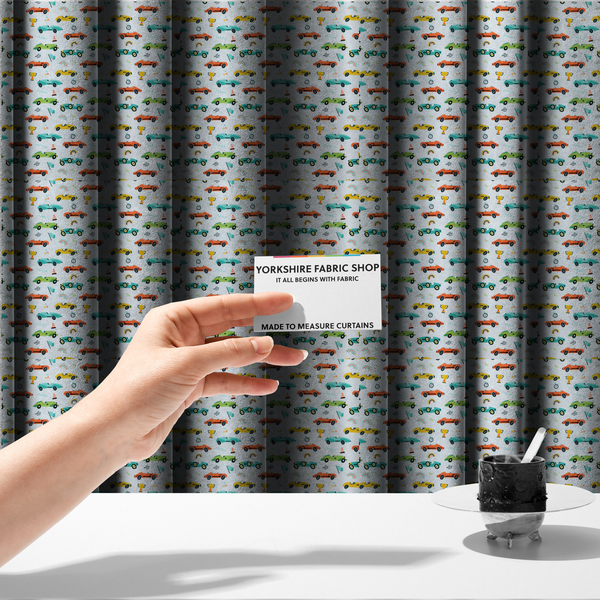 The fabric used to create these made-to-measure curtains is a fabric featuring a whimsical, repeating pattern of vintage-style racing cars and track accessories.