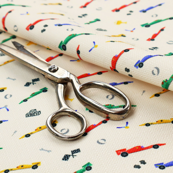 A cream-coloured fabric featuring a detailed, repeating pattern of Formula 1-style racing cars and track elements.