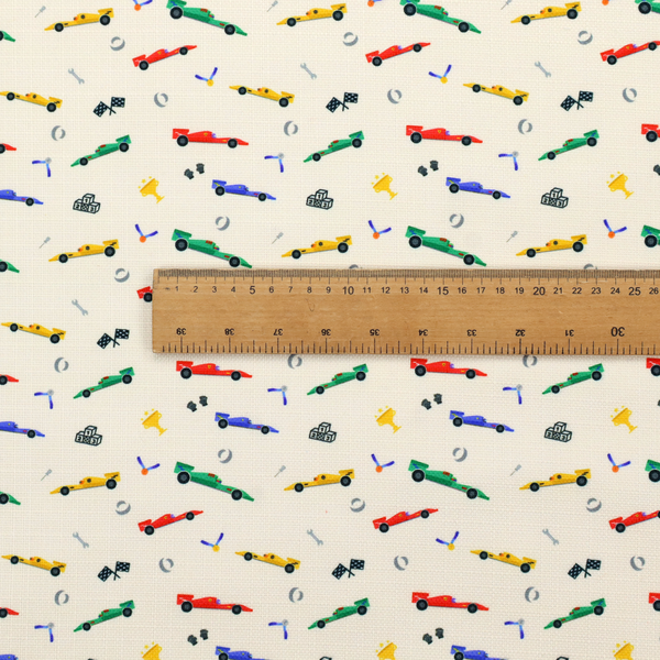 A cream-coloured fabric featuring a detailed, repeating pattern of Formula 1-style racing cars and track elements.
