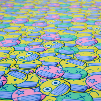 Seamless novelty fabric pattern featuring a dense, overlapping collage of cartoon emoji smiley faces wearing blue face masks in bright neon yellow, green, and pink.