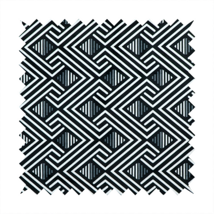 A geometric pattern featuring a repeating labyrinthine or Greek key-inspired design. The fabric has a high-contrast black and white colour scheme, with white interlocking lines forming diamond shapes and diagonal pathways against a deep black background.